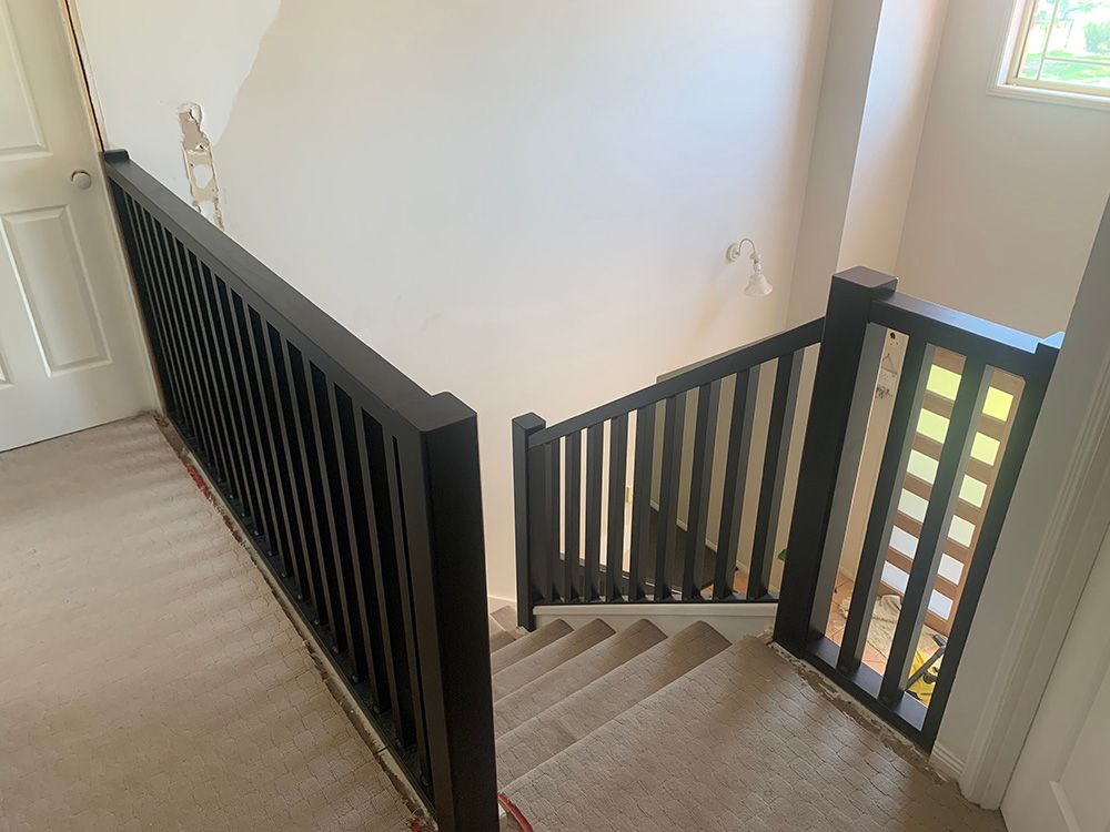 A staircase with a black railing and a window in a house. — Simmweld Metal Fabrication and Welding In Murwillumbah, NSW