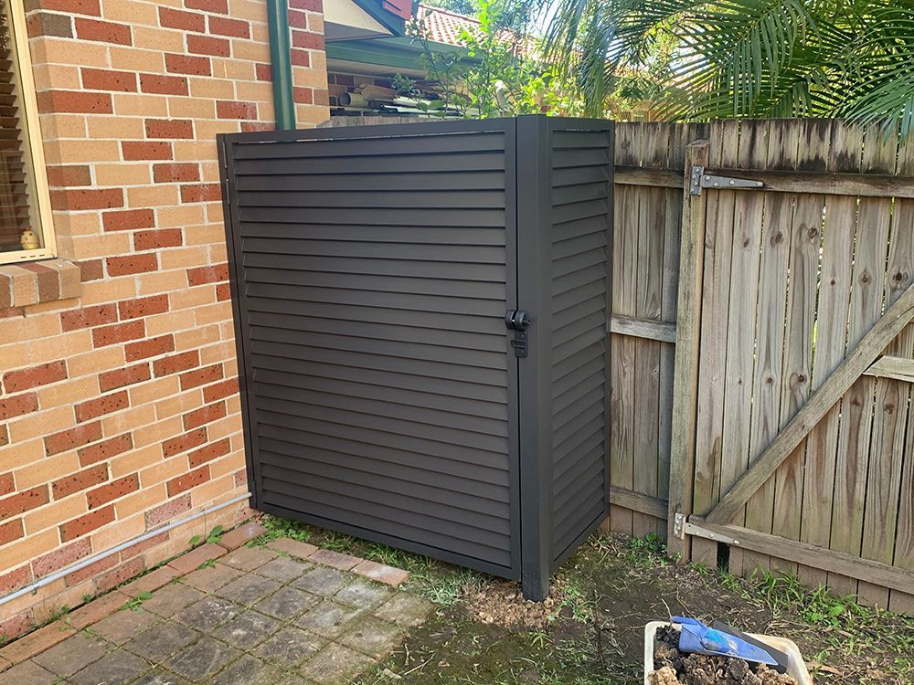 A black shed is sitting next to a brick building and a wooden fence. — Simmweld Metal Fabrication and Welding In Tweed Heads, NSW
