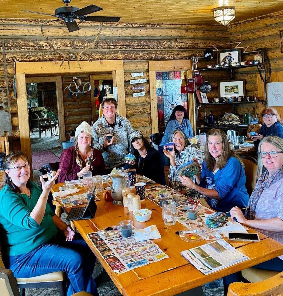 Group of people smiling around a wooden dining table in a rustic restaurant, posing for a photo