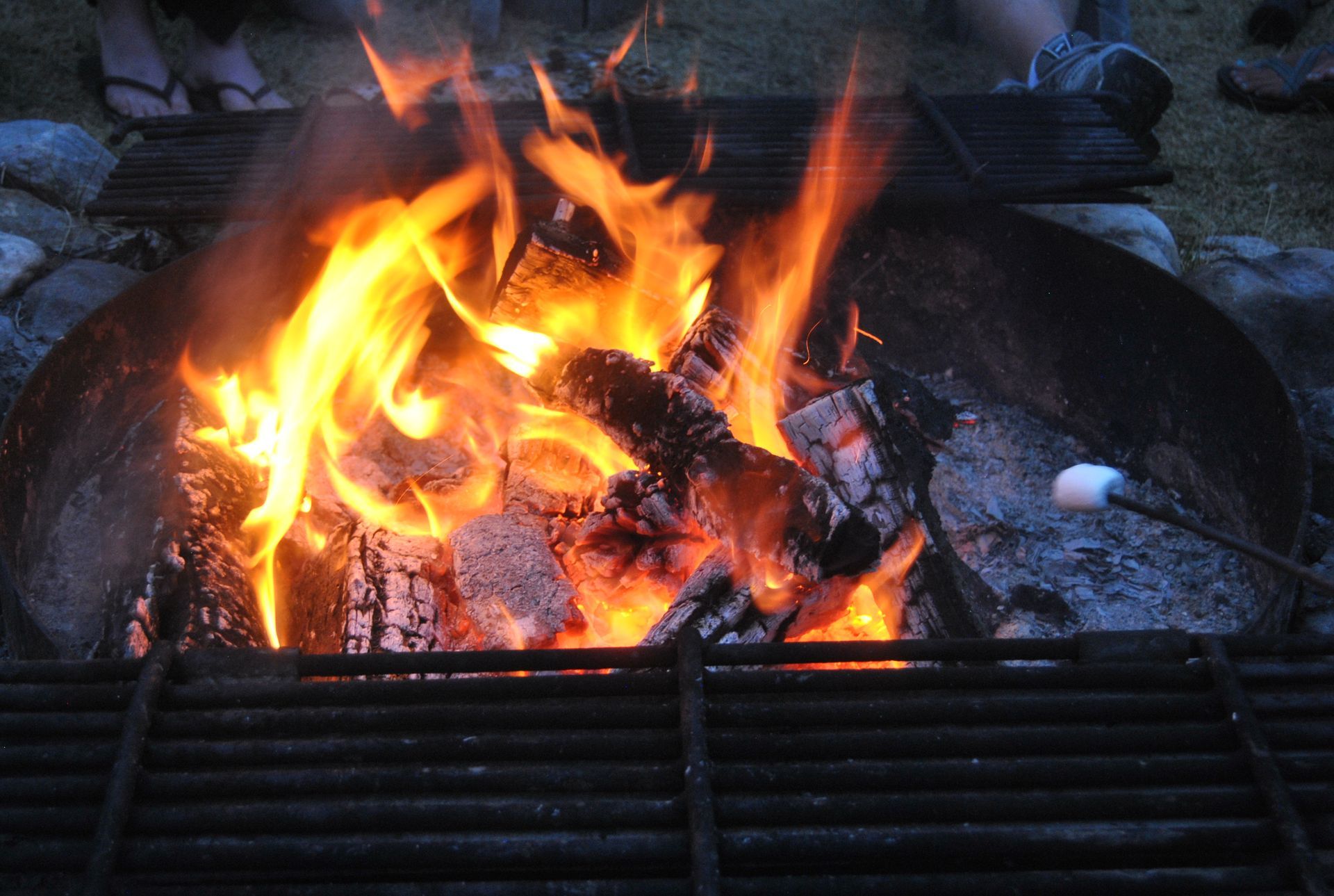 Flames burning in a charcoal grill with glowing embers and blackened logs