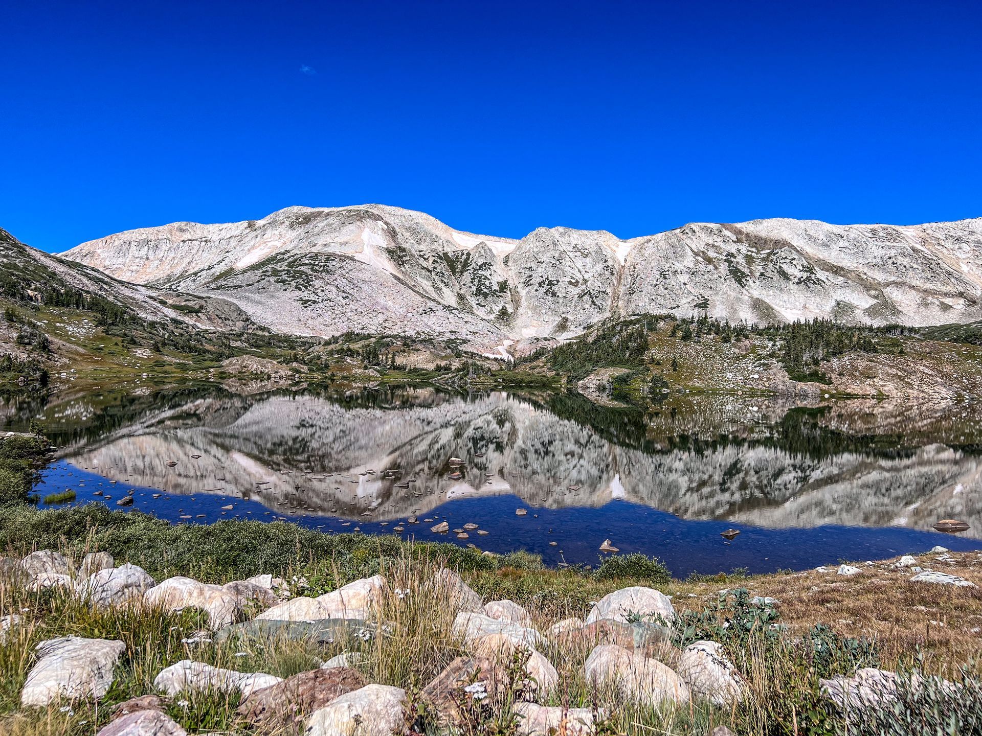 Snowy mountain reflected in a calm lake under a clear blue sky