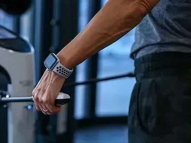A man wearing an apple watch is using a machine in a gym.