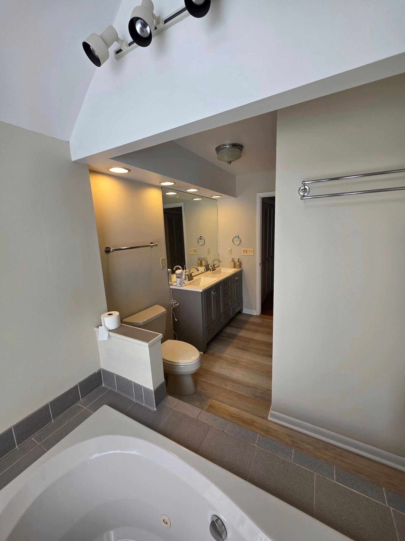 Bathroom with a jacuzzi, toilet, vanity, and neutral-colored walls and floors.