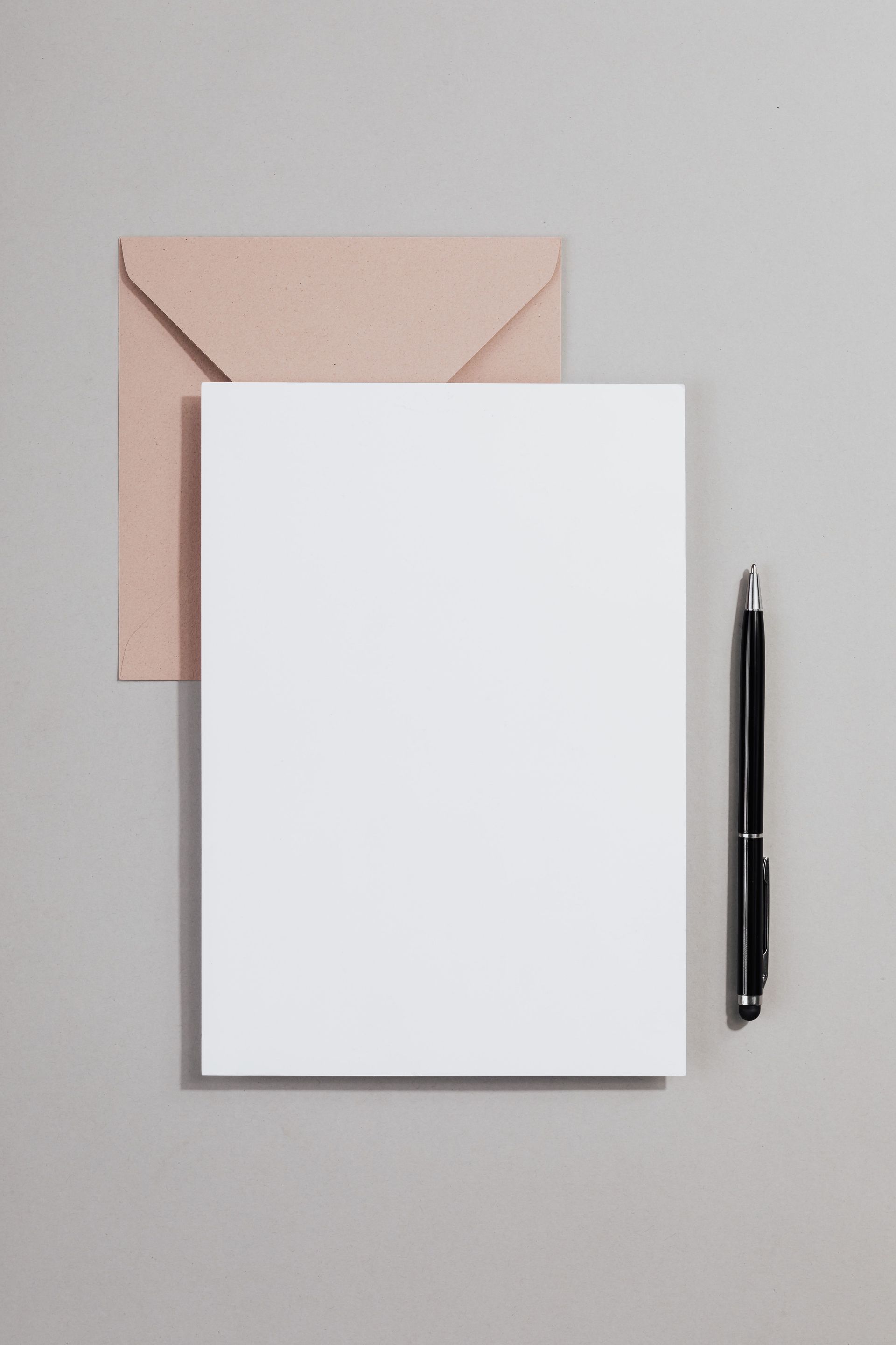 Blank notepad with envelope and pen on a gray background