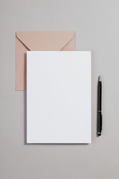 Blank notepad with envelope and pen on a gray background