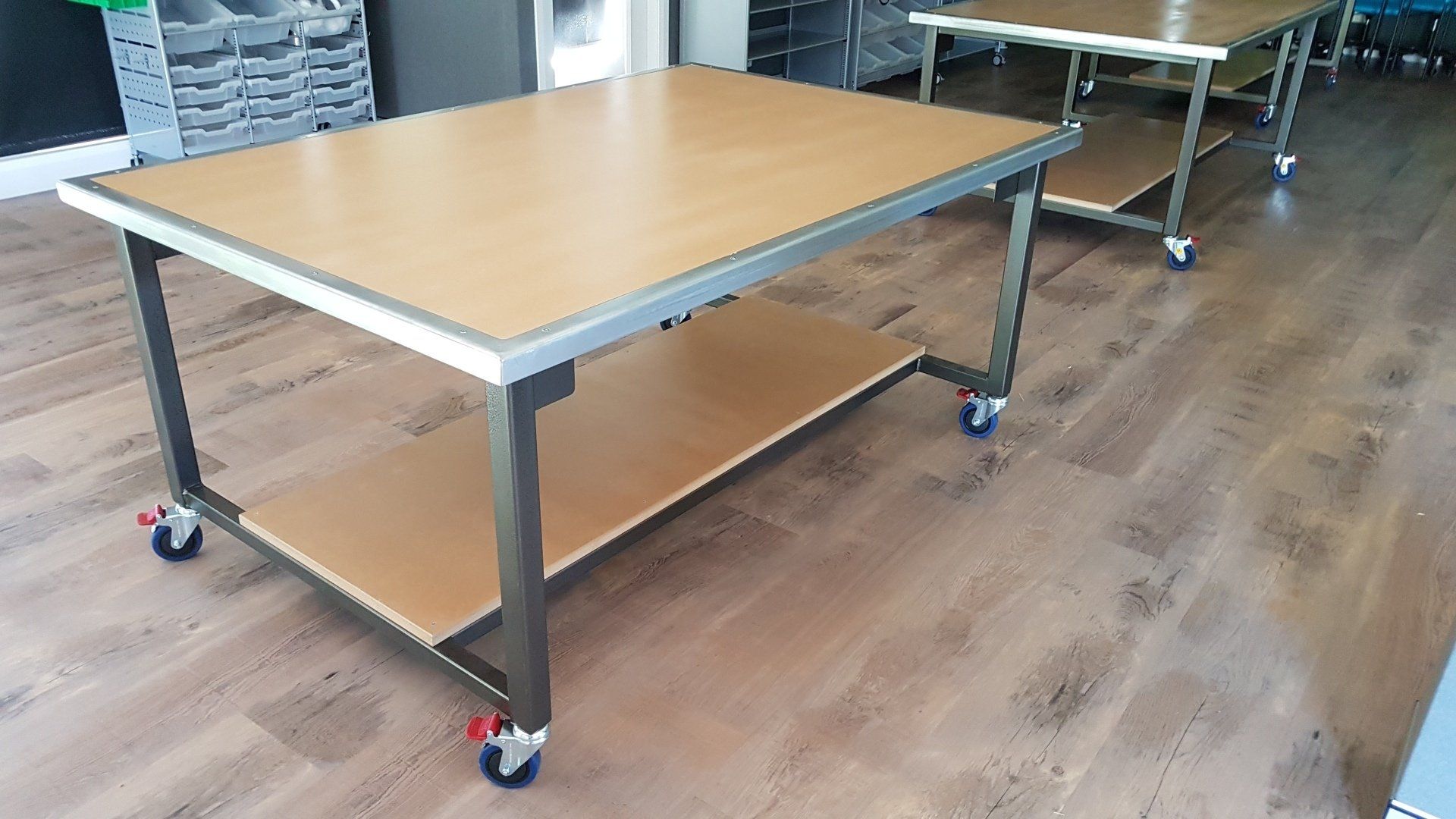 A wooden table with wheels is sitting on a wooden floor.