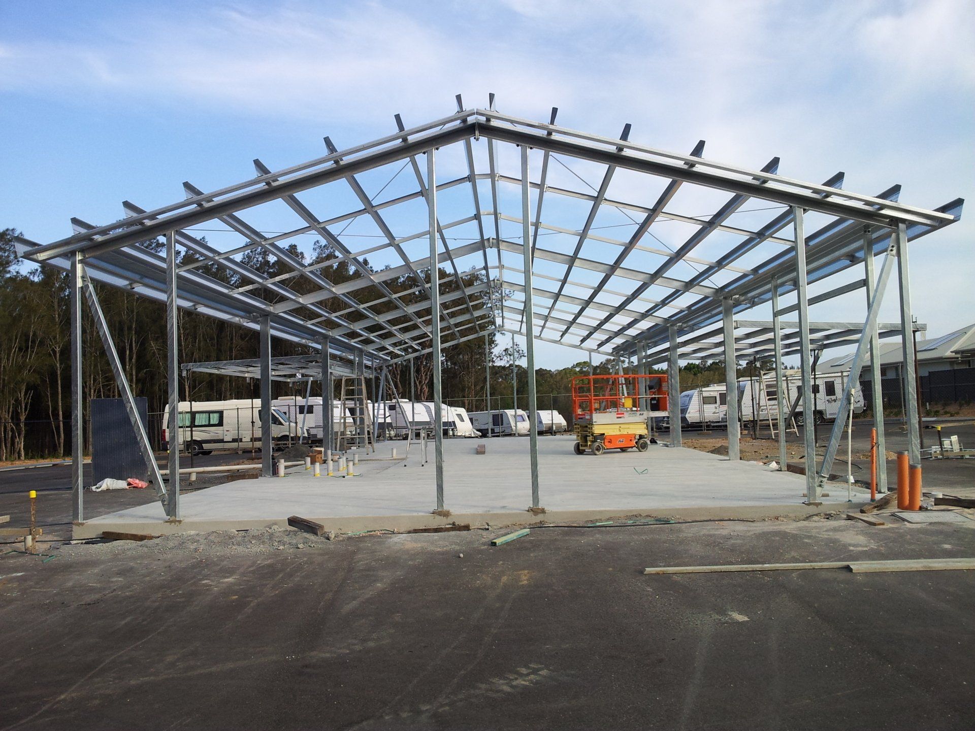A large metal structure is being built in a parking lot