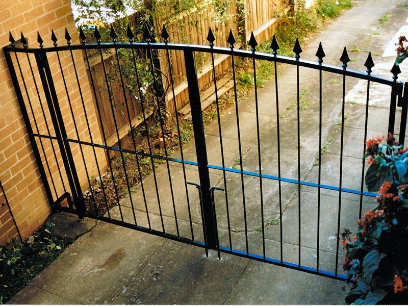 A wrought iron gate with a brick wall in the background