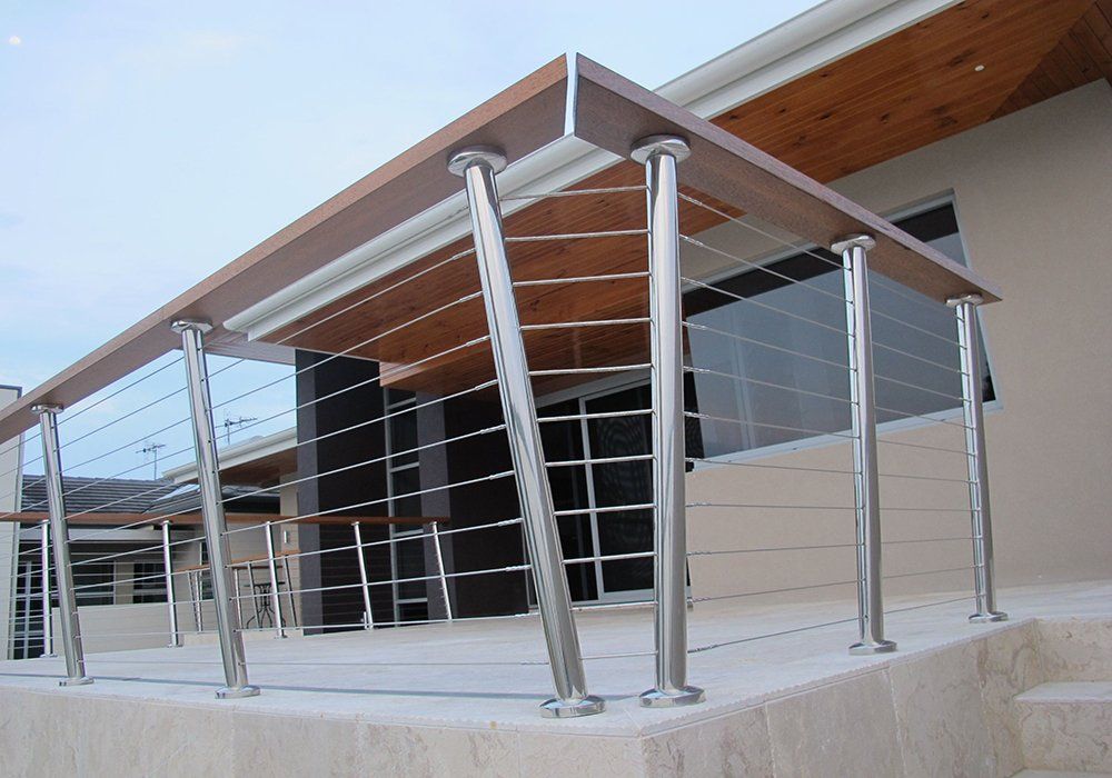A balcony with a stainless steel railing and wooden handrails