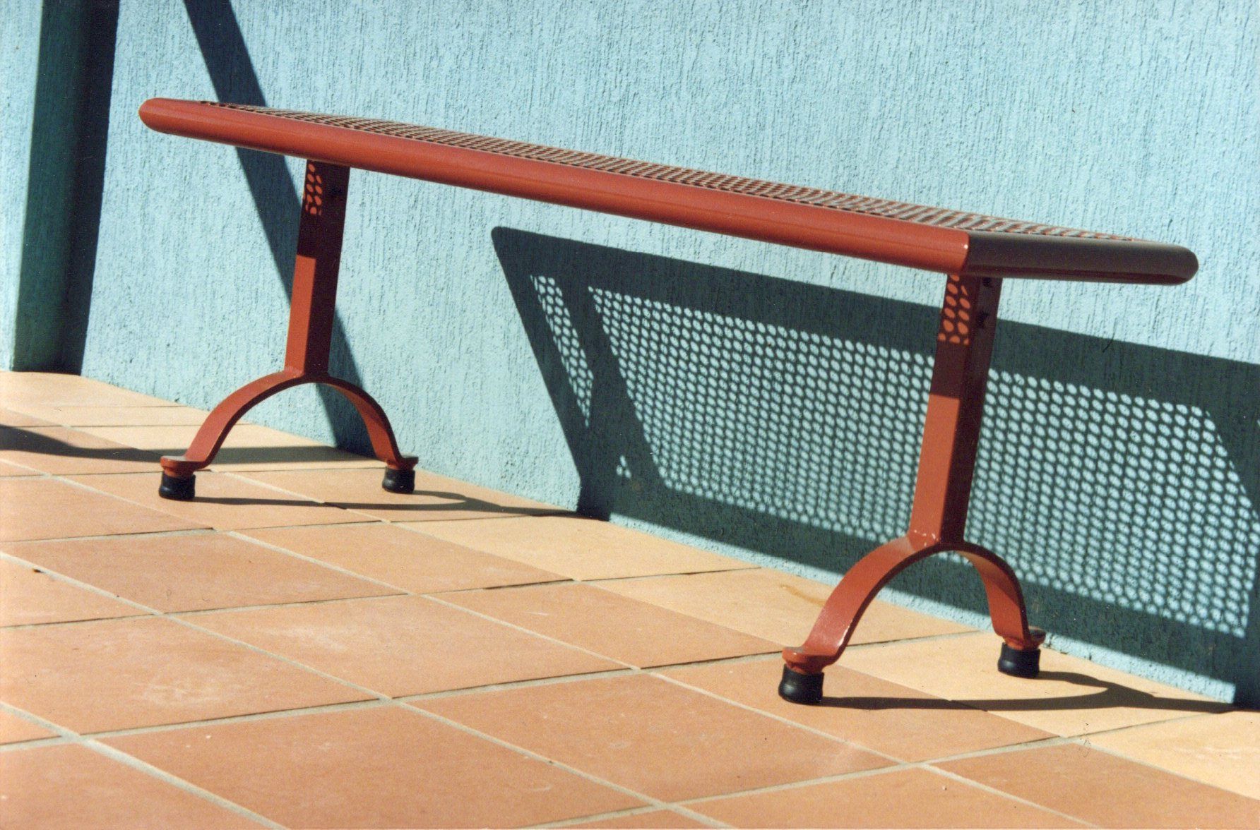 A red bench is sitting in front of a blue wall