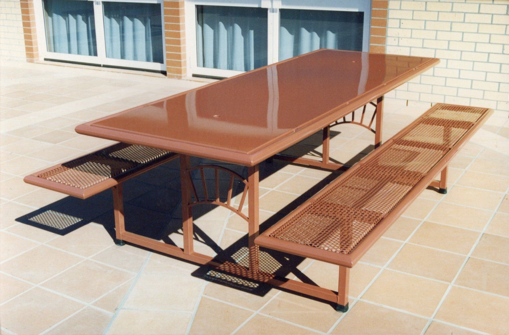 A picnic table with two benches on a tiled patio