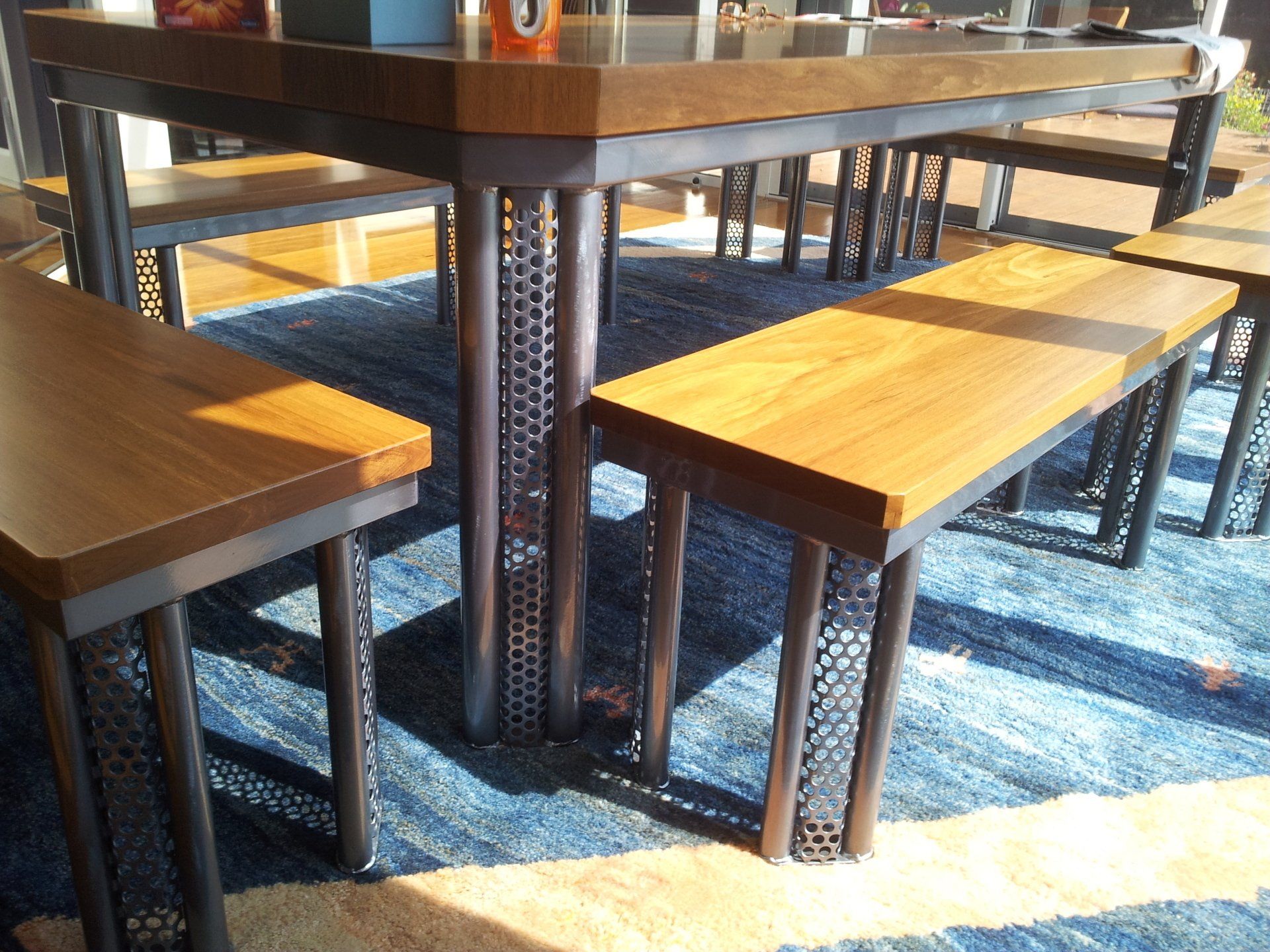 A wooden table and benches on a blue rug