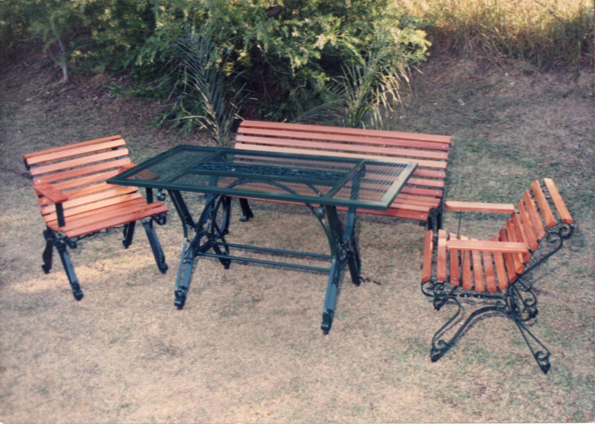 A table with two chairs and a bench in the grass