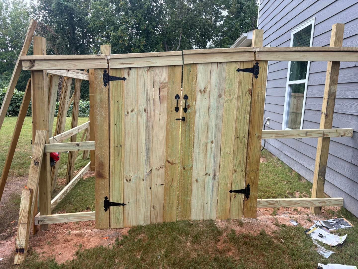 Wooden shed under construction with open double doors and unfinished framing in a backyard