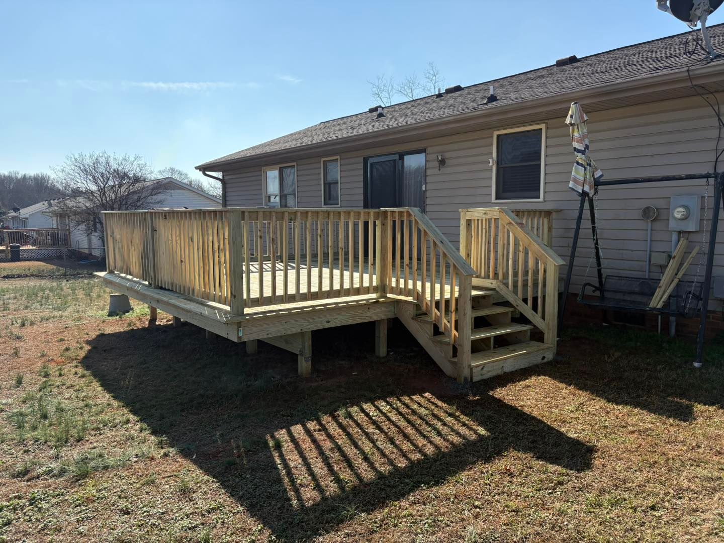Wooden wheelchair ramp and steps attached to the back of a house in a grassy yard