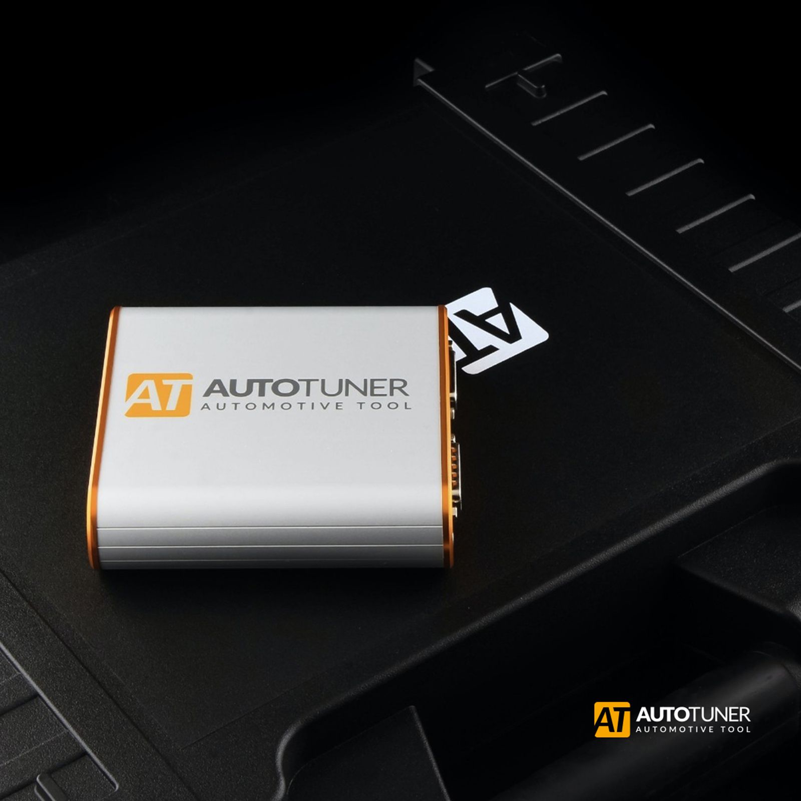 Silver AUTOTUNER automotive tuning device with orange trim on a black surface
