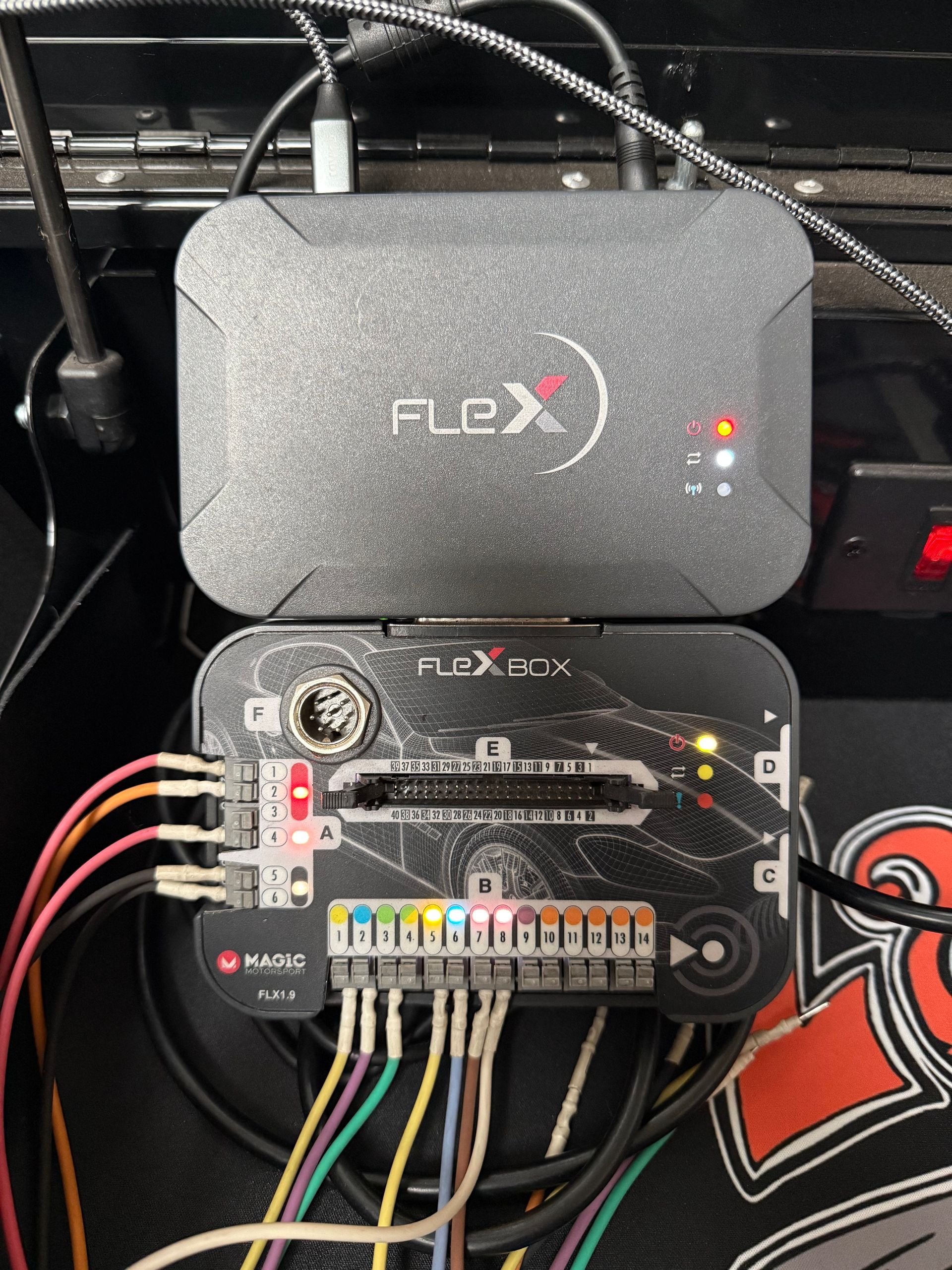 Close-up of a mounted black FLEX controller box with connected wires and illuminated indicator light.