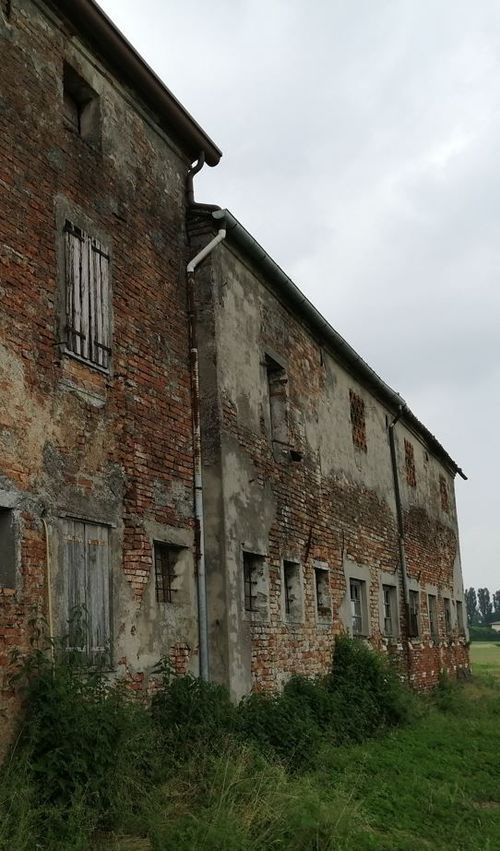 Un vecchio edificio in mattoni con molte finestre si trova in mezzo a un campo erboso.
