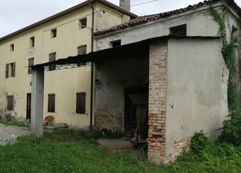Un piccolo edificio con un muro di mattoni si trova di fronte a un grande edificio.