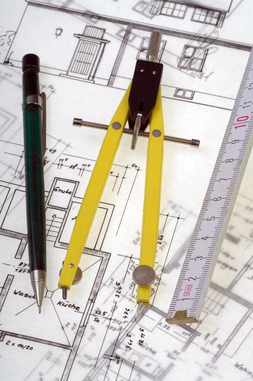 Un compasso e un righello sono sopra il disegno di una casa
