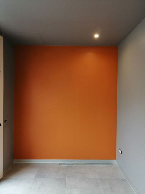 Una stanza vuota con una parete arancione e un soffitto grigio.