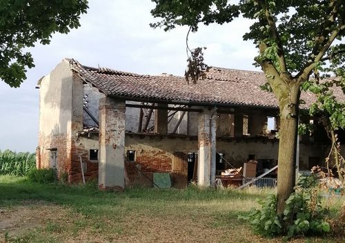 Un edificio in mattoni con un tetto di tegole è circondato da erba e alberi