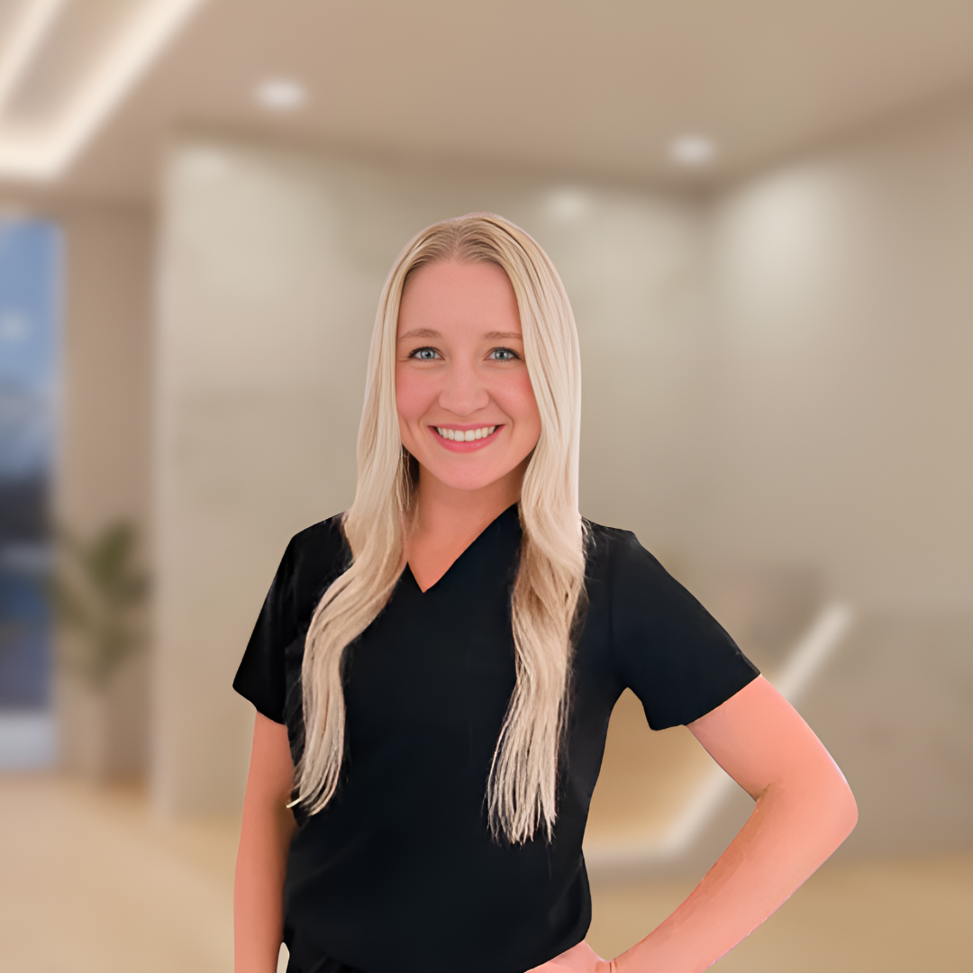 Smiling woman in a black shirt standing in a bright office lobby with a blurred background