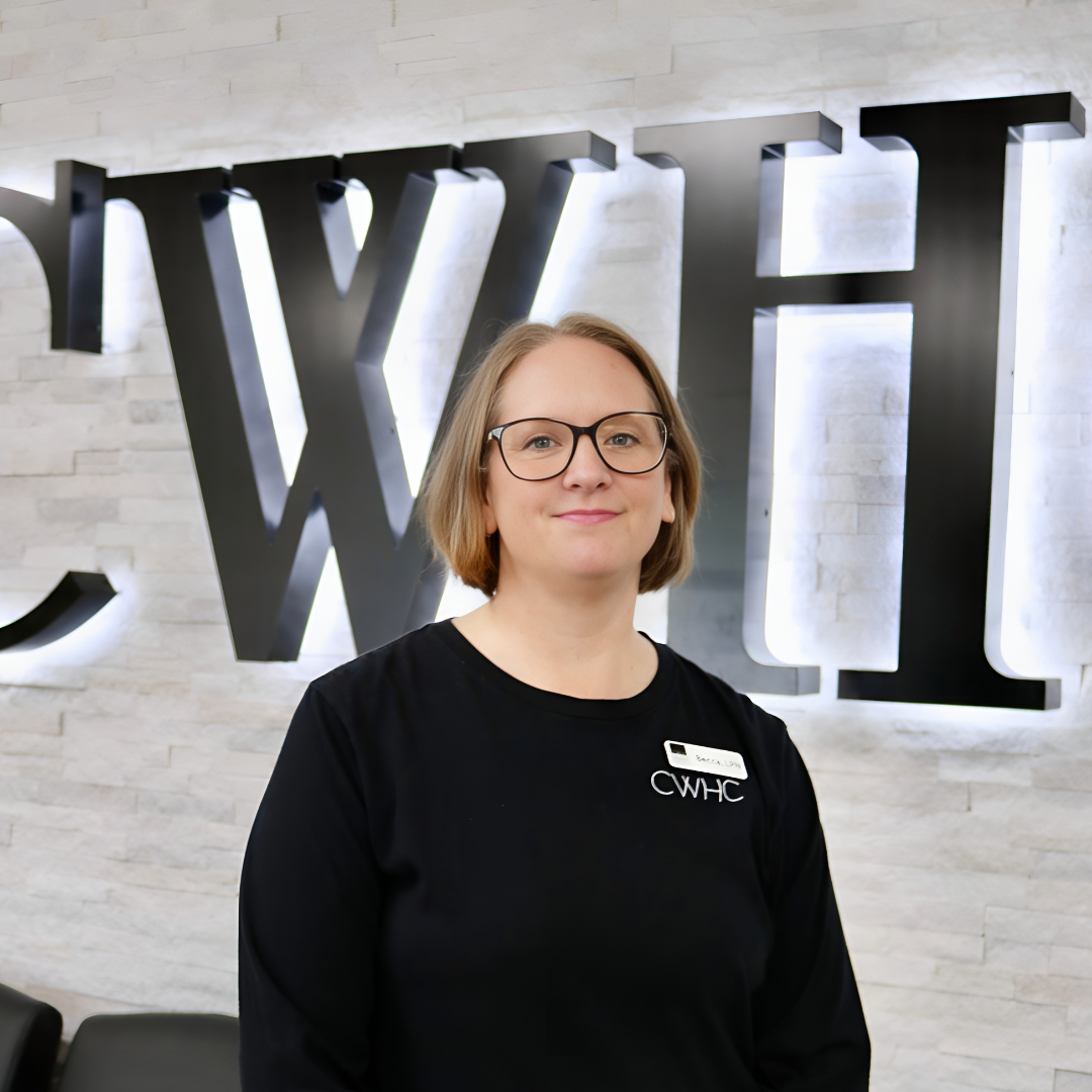 Woman in glasses standing in front of a backlit wall sign