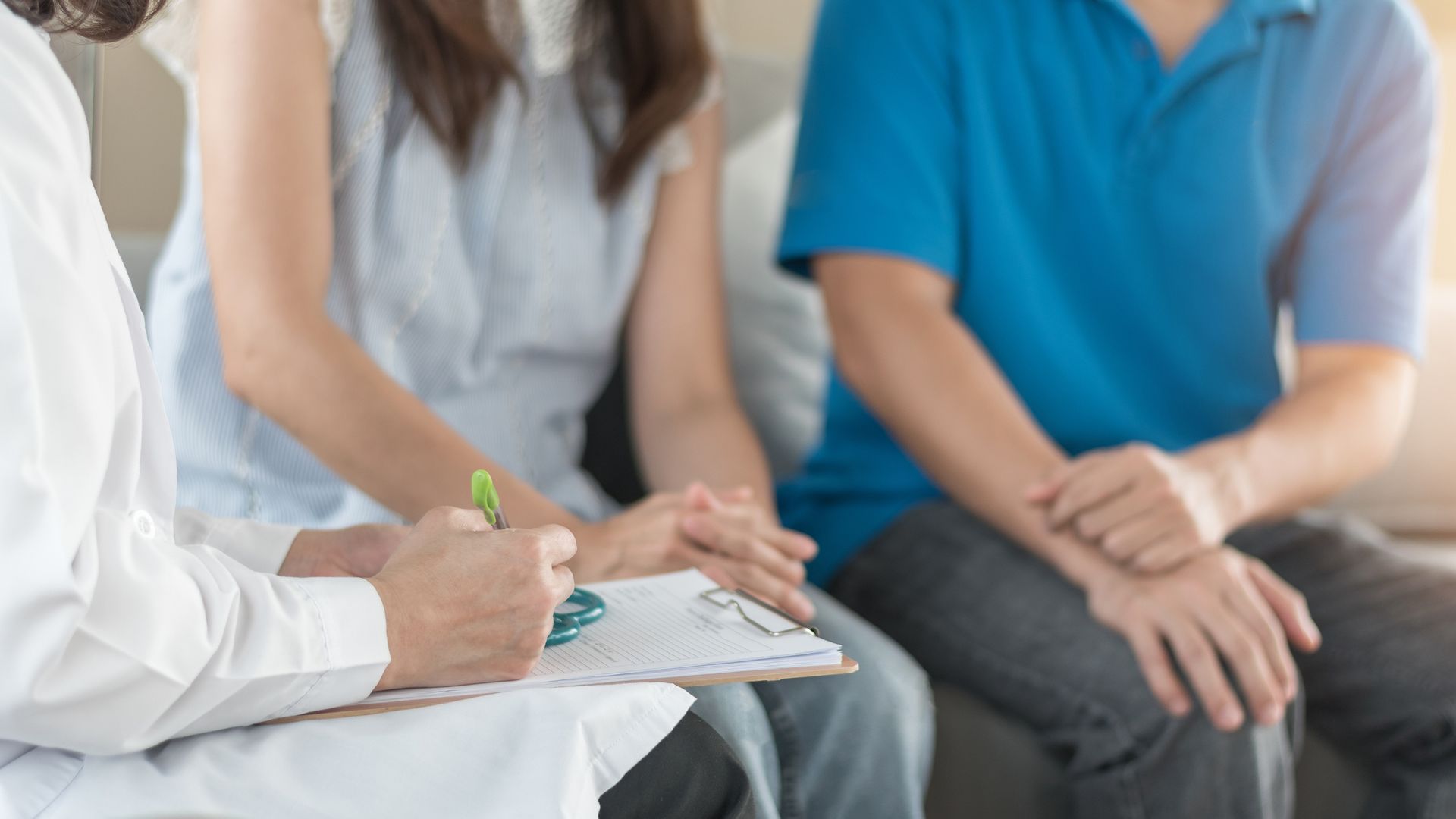 People seated in a meeting, with a clinician taking notes on a clipboard.