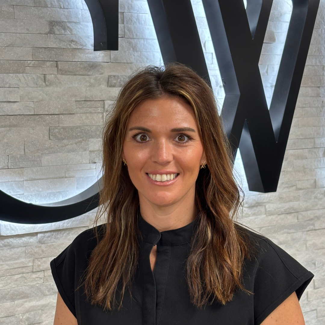 Portrait of a smiling woman standing before a stone wall with large black letters