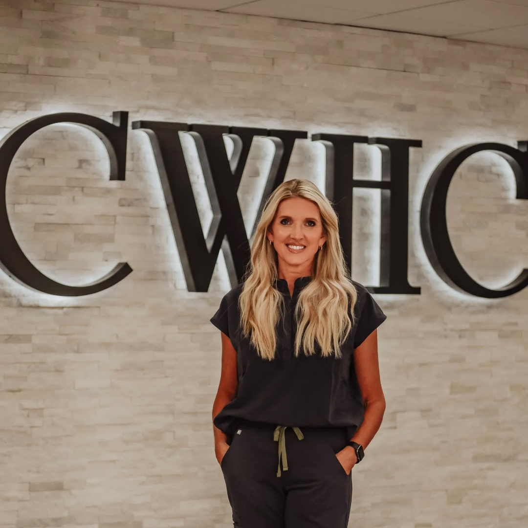 Woman standing in front of a CWHC sign, smiling in a black outfit