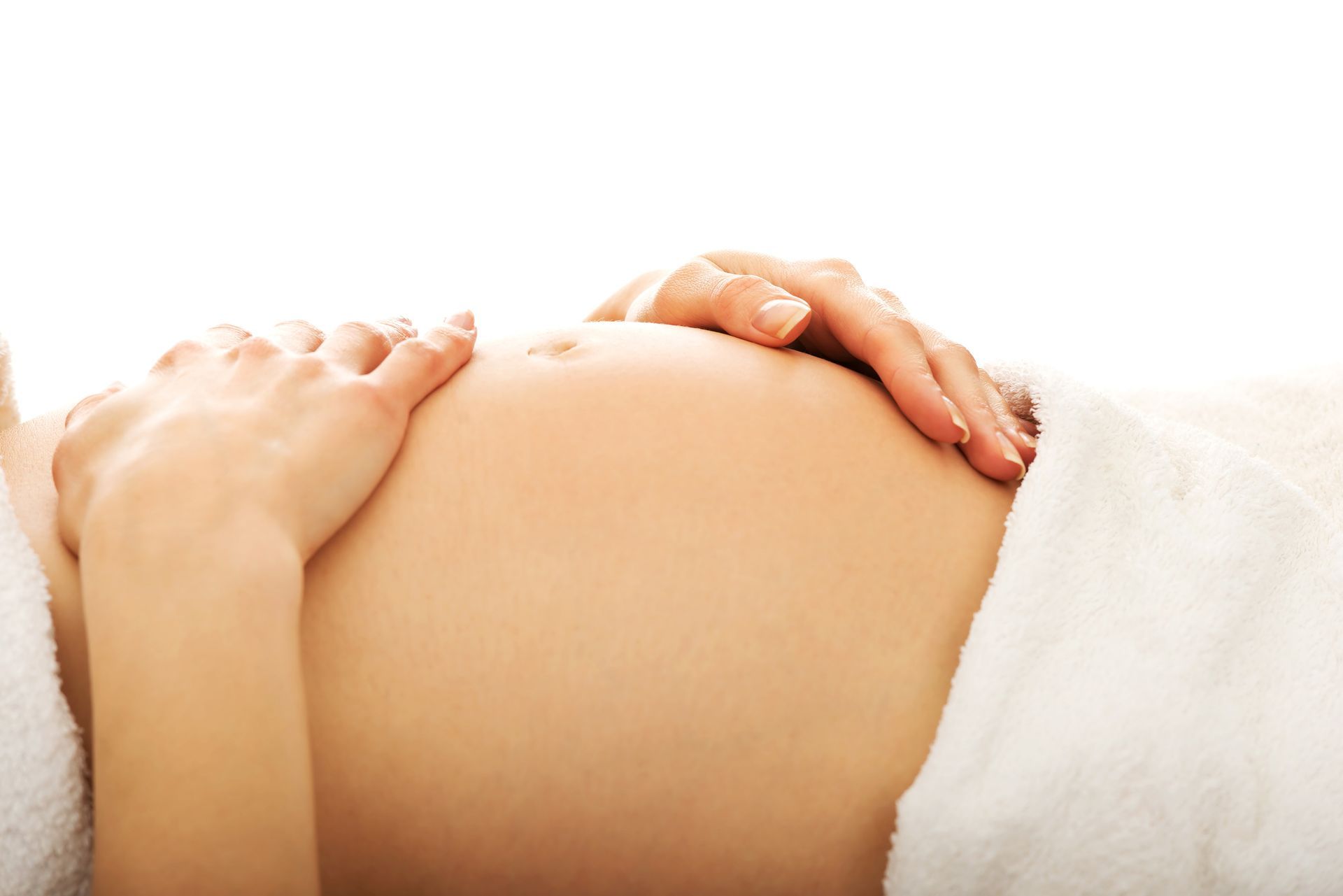 Hands on a pregnant belly with a white towel on the side
