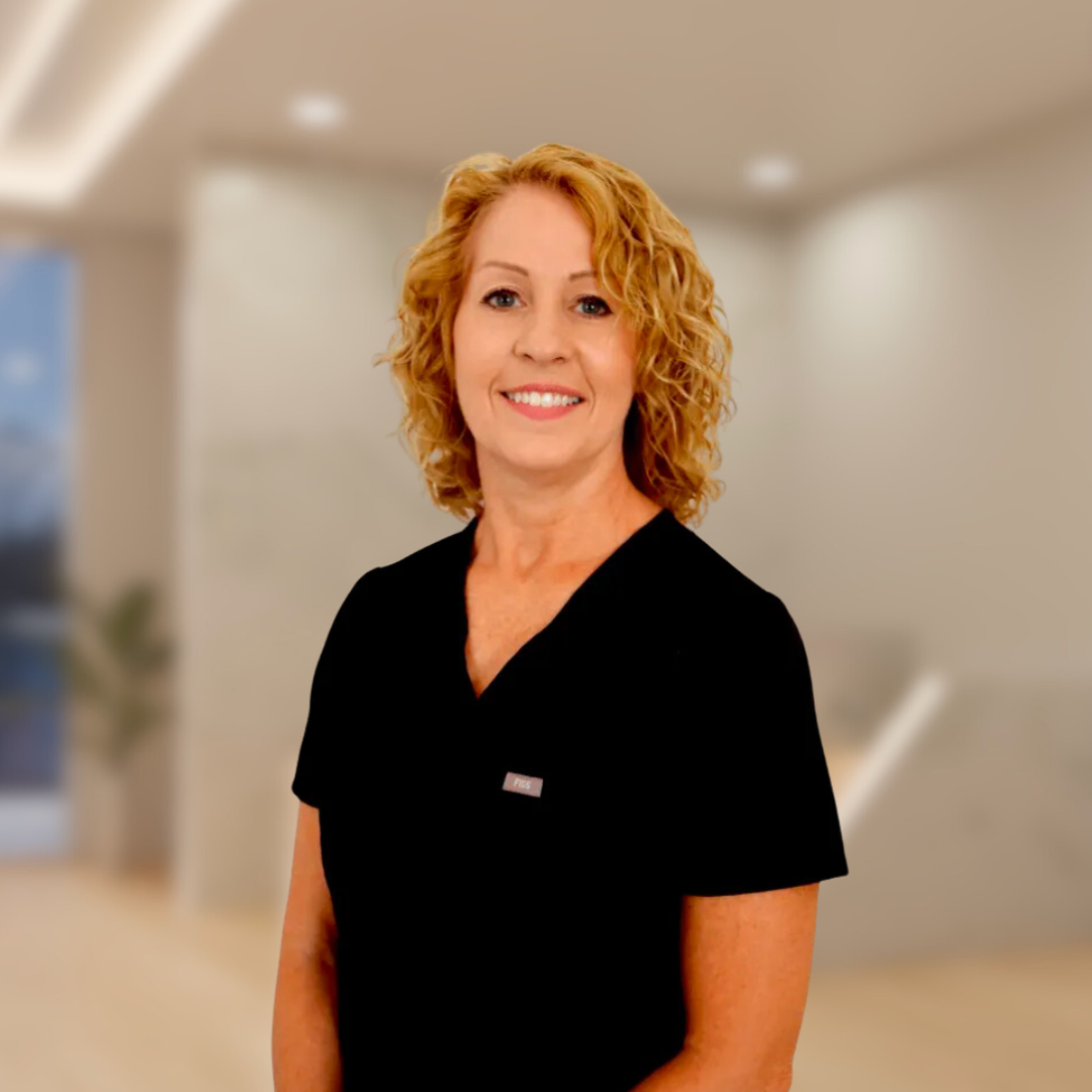 Smiling person in a black shirt standing in a blurred office hallway