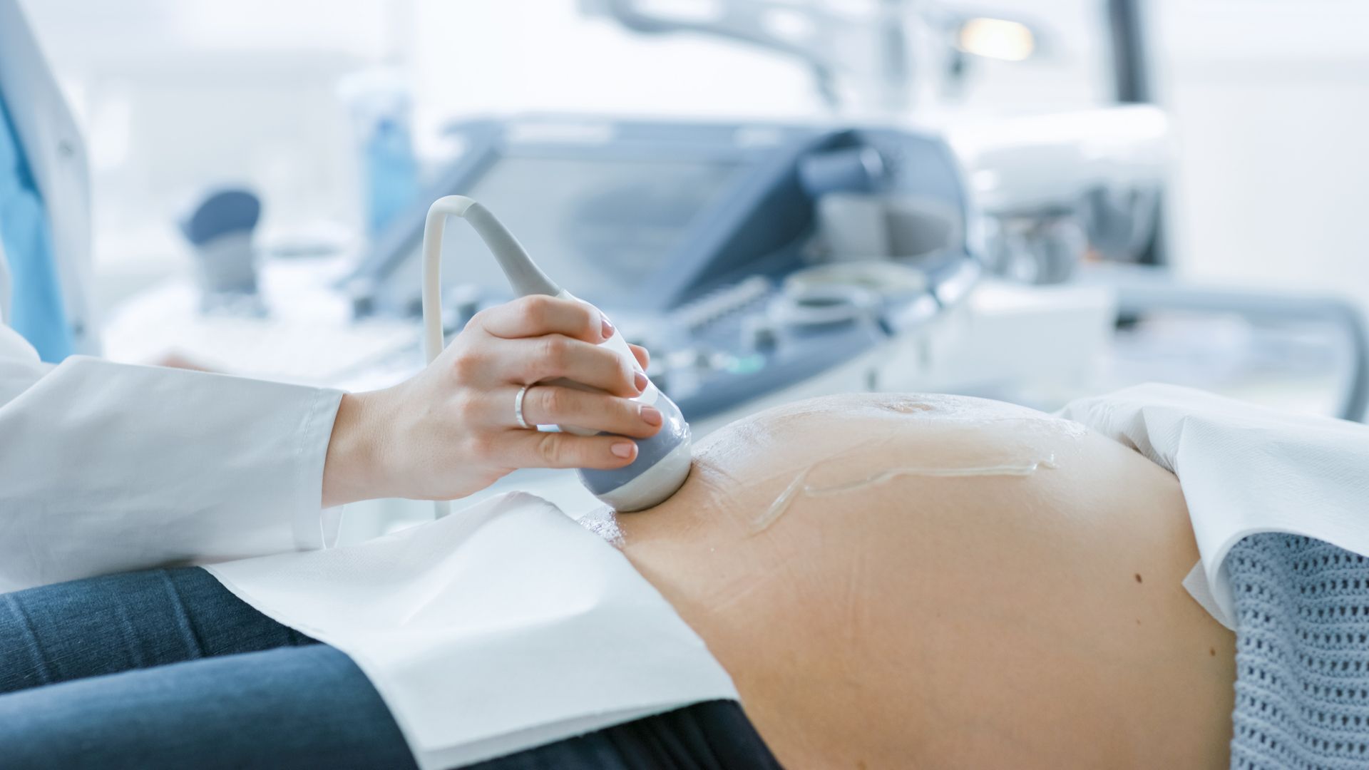 Doctor performing prenatal ultrasound on pregnant patient in a hospital bed