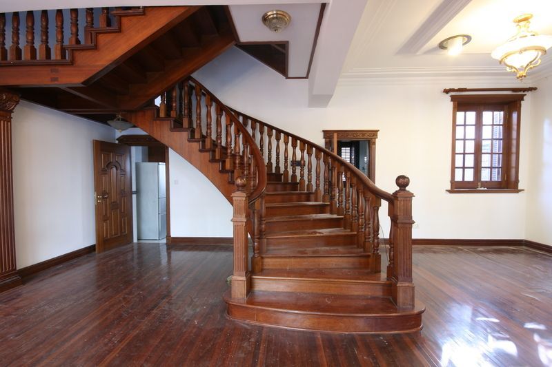 Beautifully refinished mahogany curved staircase surrounded by mahogany plank flooring