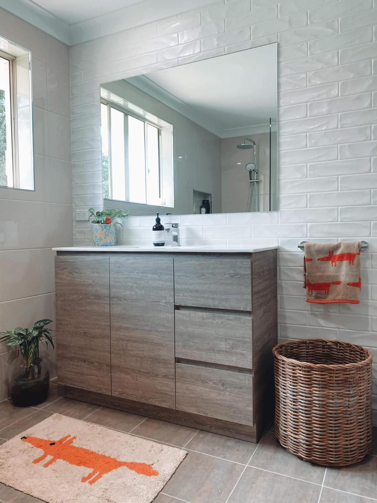 A Bathroom with A Sink, Mirror, and A Rug with A Fox on It — Aqua Blue Plumbing Services in Coffs Harbour, NSW