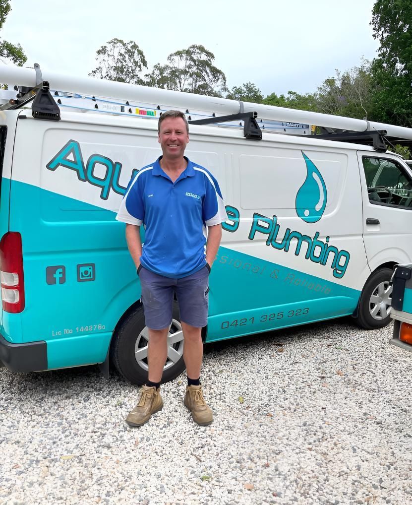 A Man Is Standing in Front of Van — Aqua Blue Plumbing Services in Coffs Harbour, NSW 