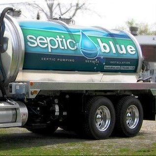 A septic blue truck is parked in a grassy field.