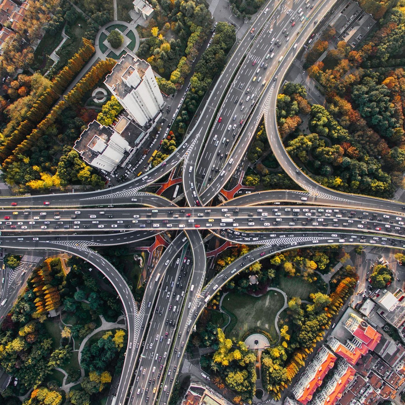 An aerial view of a busy highway intersection surrounded by trees and buildings.