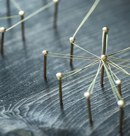 A bunch of nails and strings are connected to each other on a wooden table.