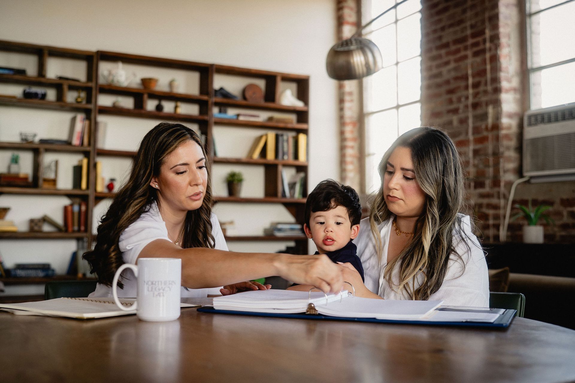 Three people at a table reviewing papers in a cozy home office