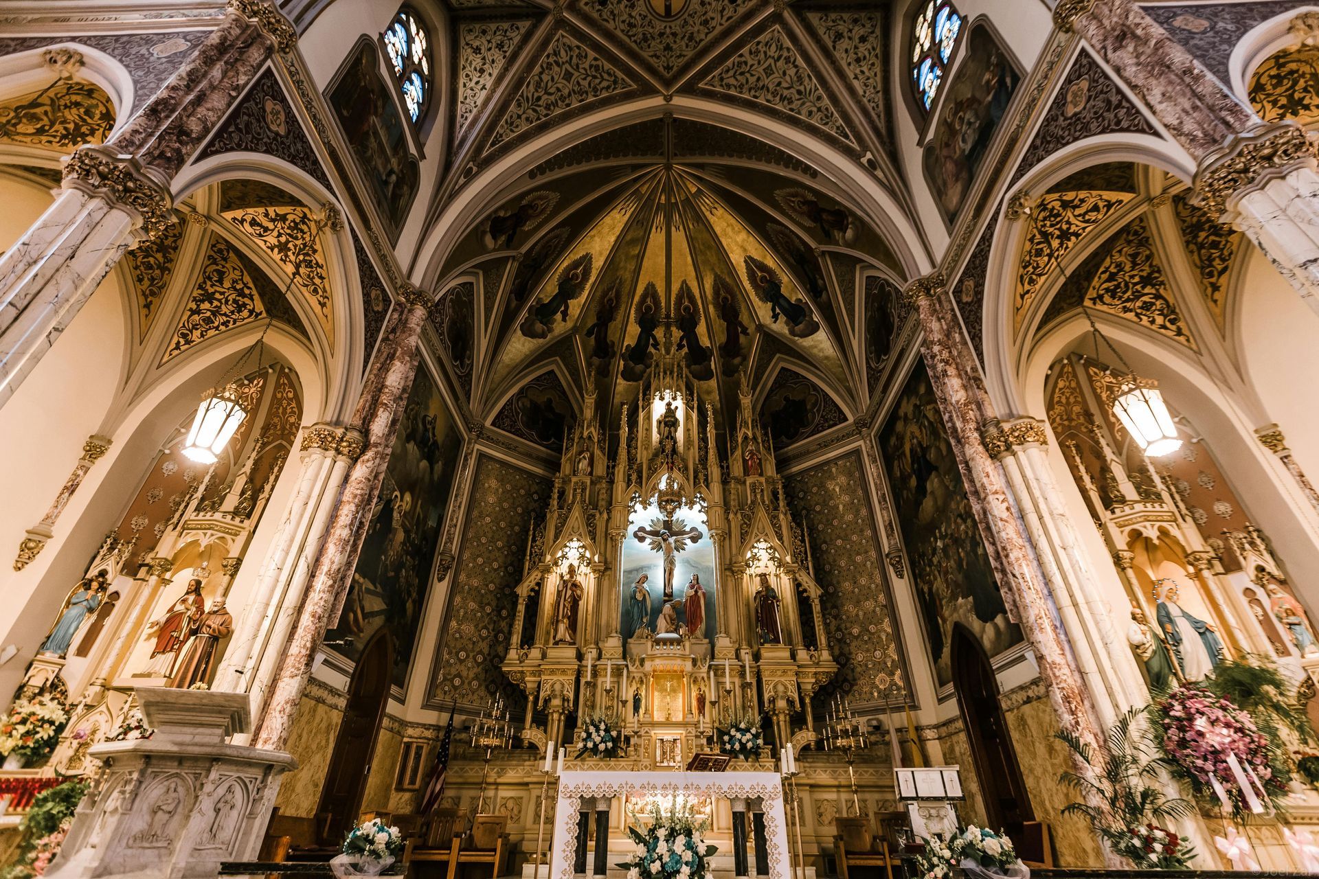 An ornate altar inside a cathedral, featuring Gothic arches, vaulted ceilings, and warm lighting throughout the nave.