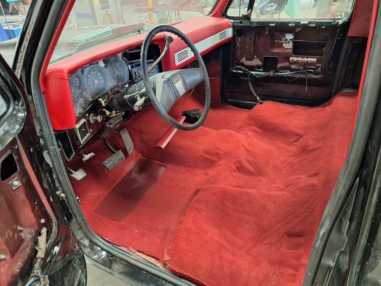 The inside of a car with red carpet and a steering wheel