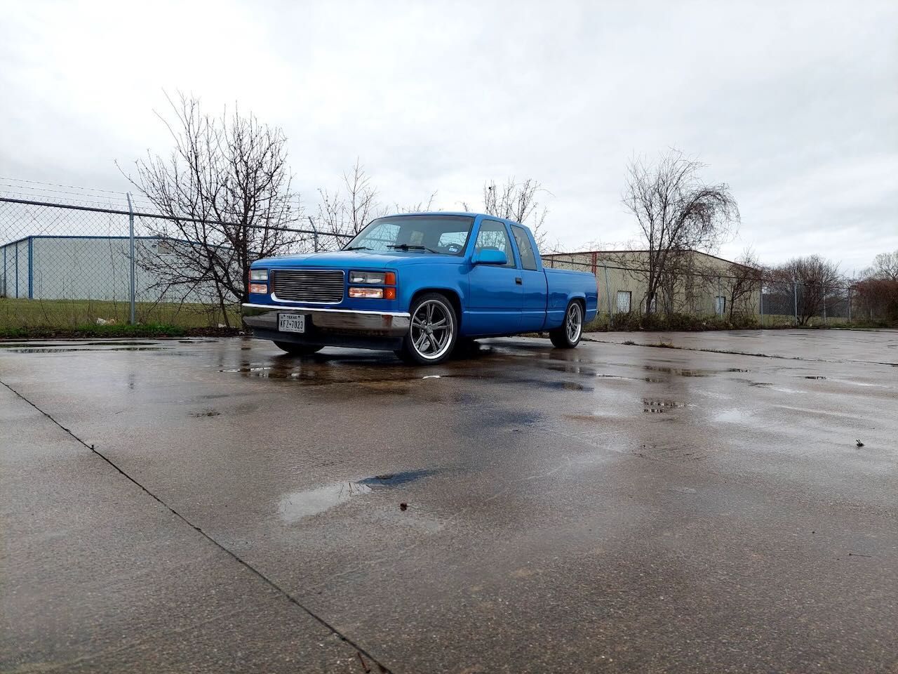 A blue truck is parked in a wet parking lot