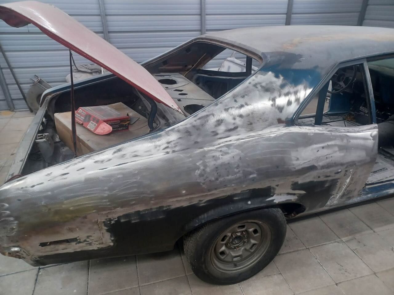A car with the hood up is sitting in a garage