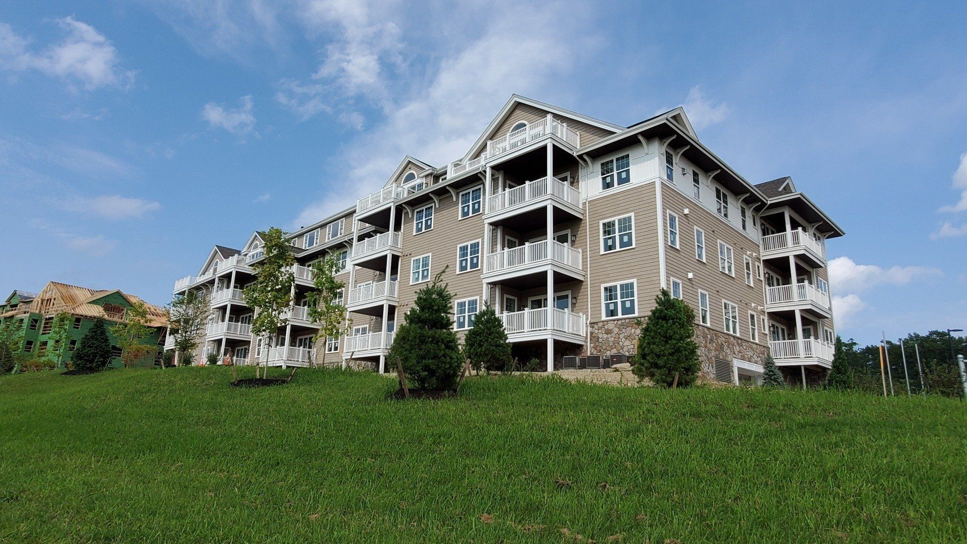 A large apartment building is sitting on top of a grassy hill.