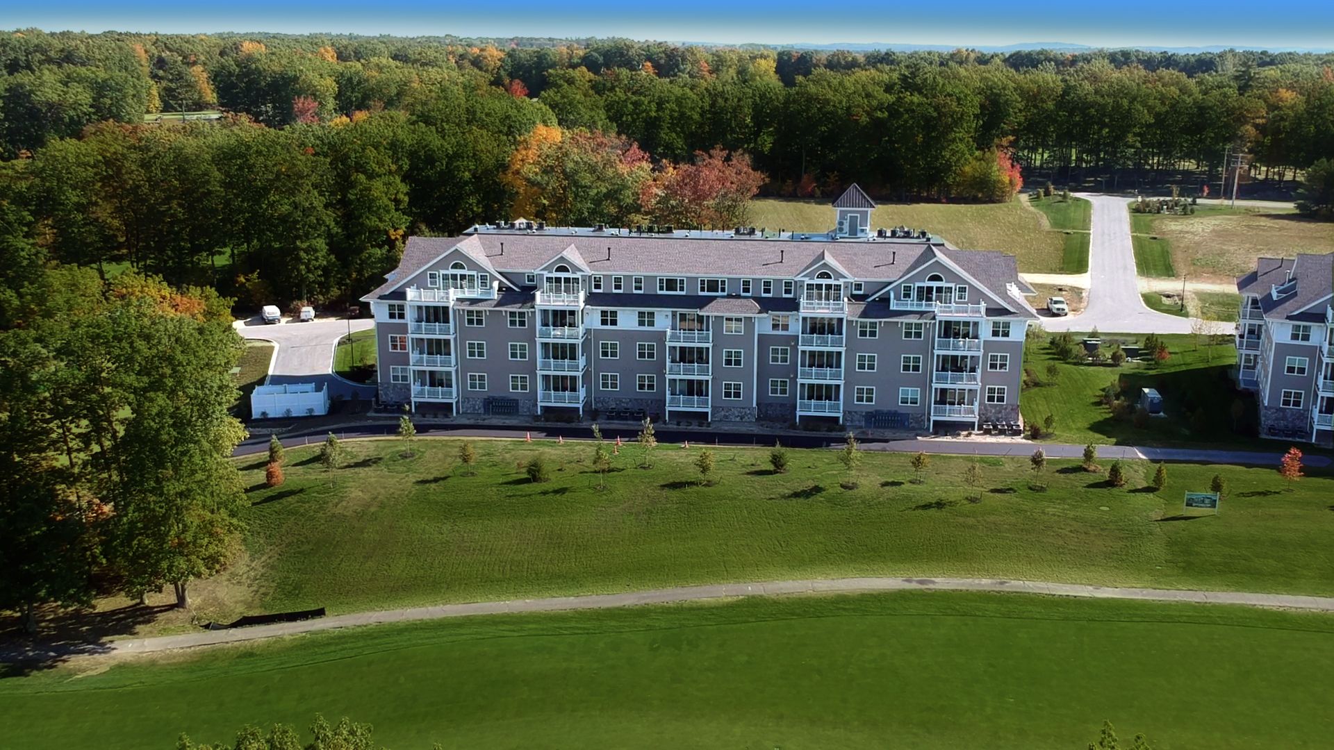 An aerial view of a large condo building surrounded by trees and grass.
