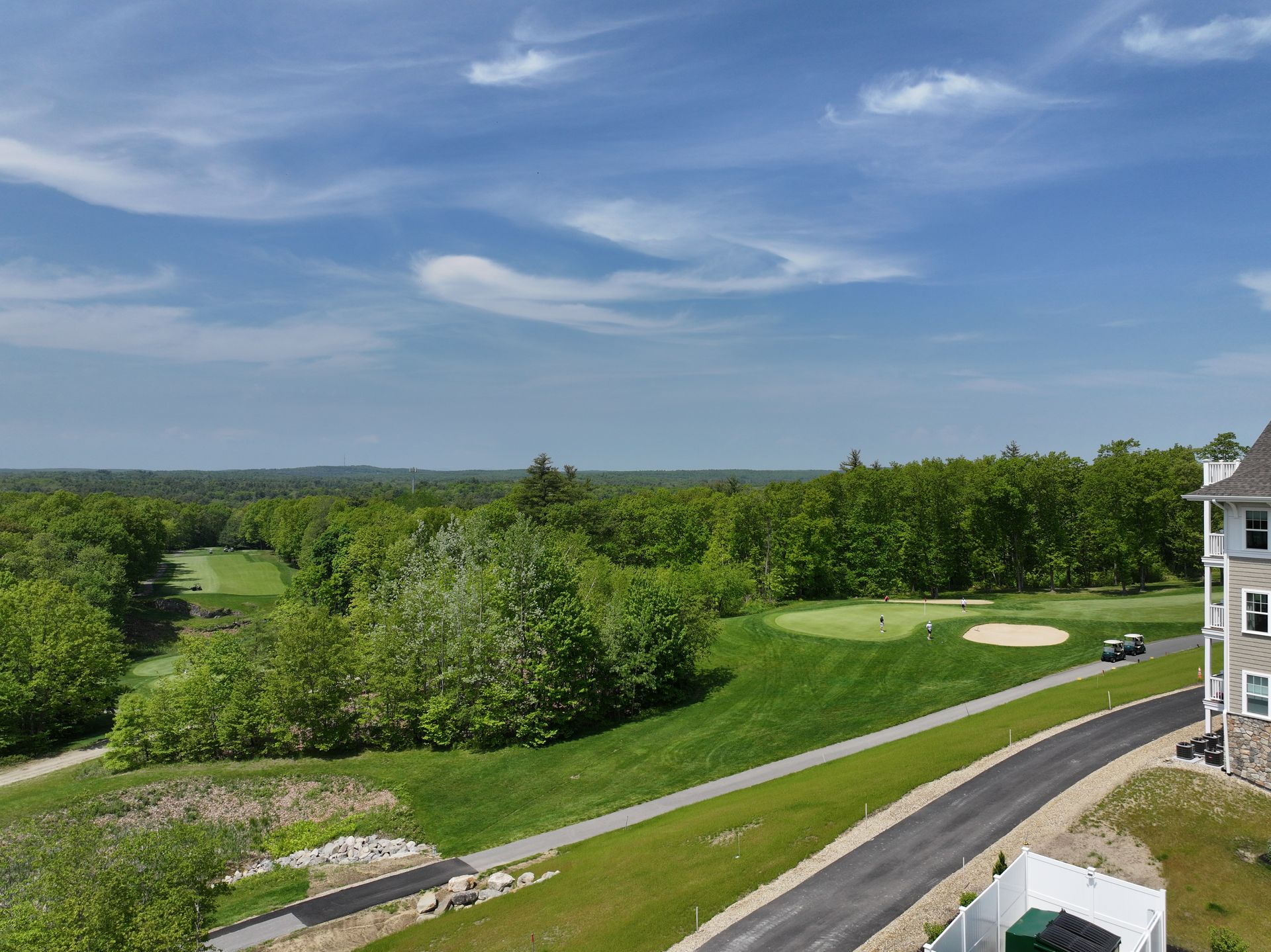 An aerial view of a golf course with a house in the foreground