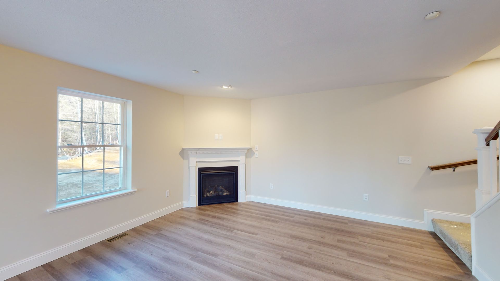 An empty living room with a fireplace and stairs.