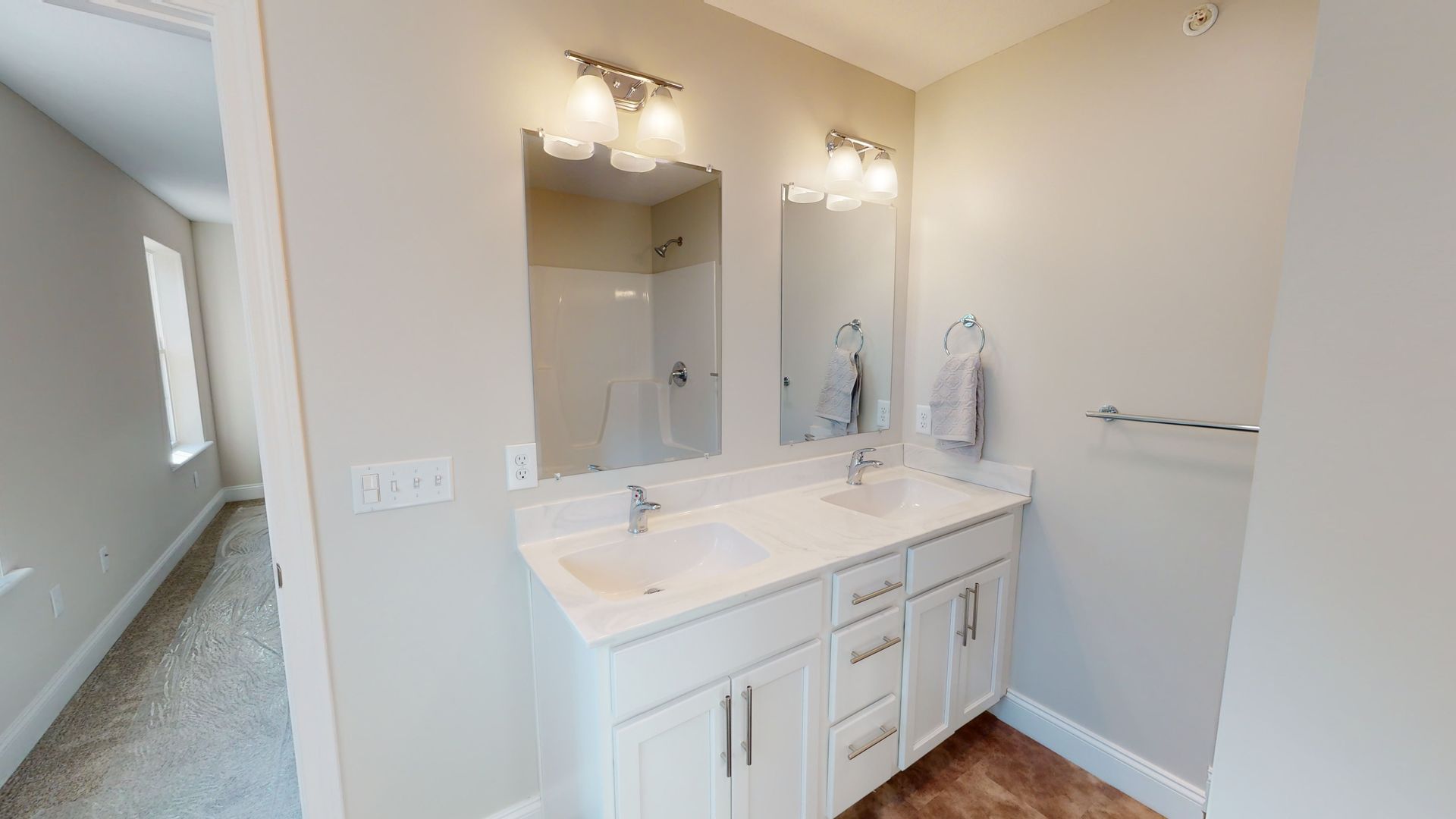 A bathroom with two sinks , two mirrors and a walk in shower.